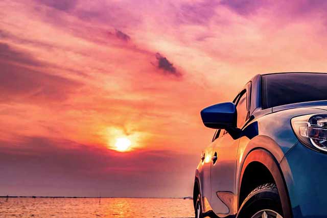 car driving into sunset