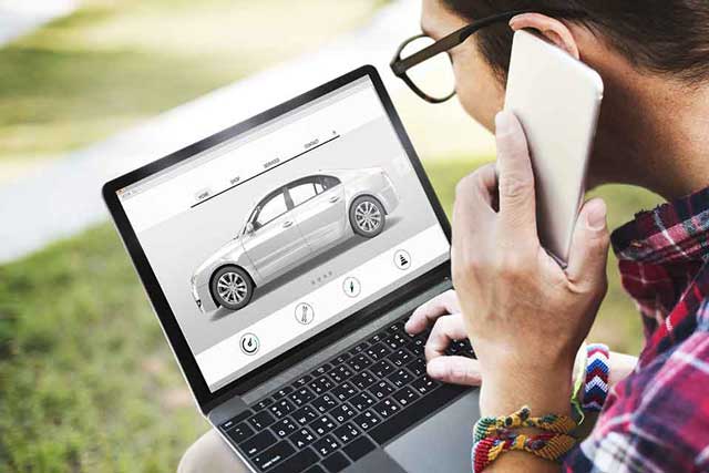 miniature car model on money next to a calculator and pencil